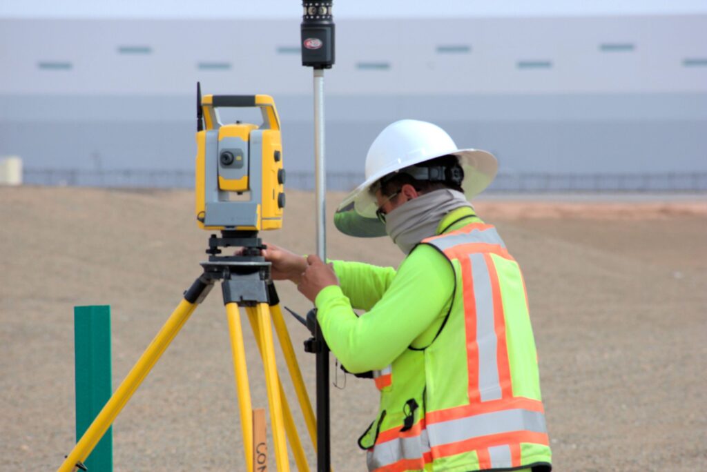 A Team Professional Associates field surveyor verifying and calibrating a total station setup during active construction staking operations in Arizona. Photo by Jackson Kern.