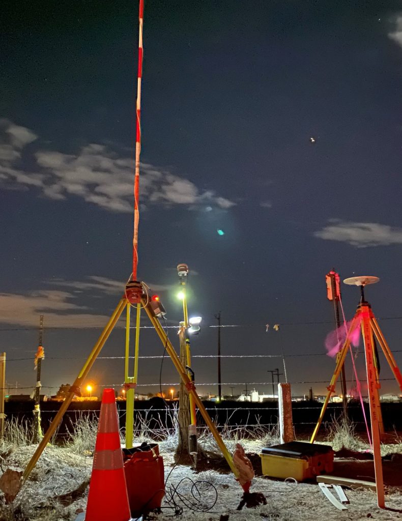 A Team Professional Associates field crew conducting a GNSS control survey near a railroad corridor at night, utilizing tripods, receivers, and safety lighting. Photo by Nathan Robinson.